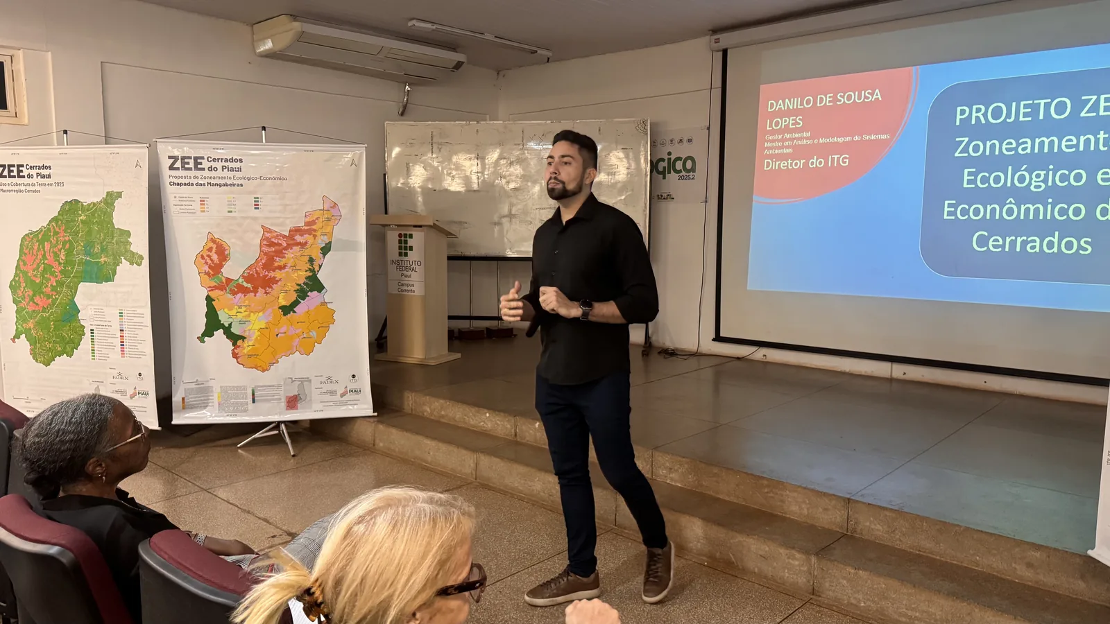 Técnico da ITG apresenta o Zoneamento Ecológico-Econômico dos Cerrados em auditório, ao lado de dois mapas impressos do zoneamento em cavaletes.